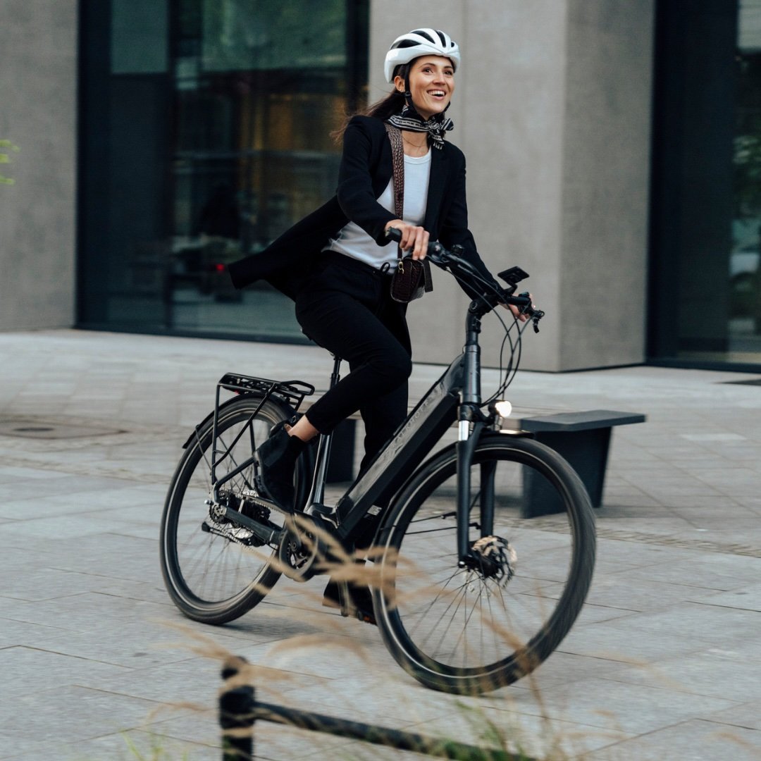 Frau fährt lachend mit ihrem Kalkhoff E-Bike durch die Stadt