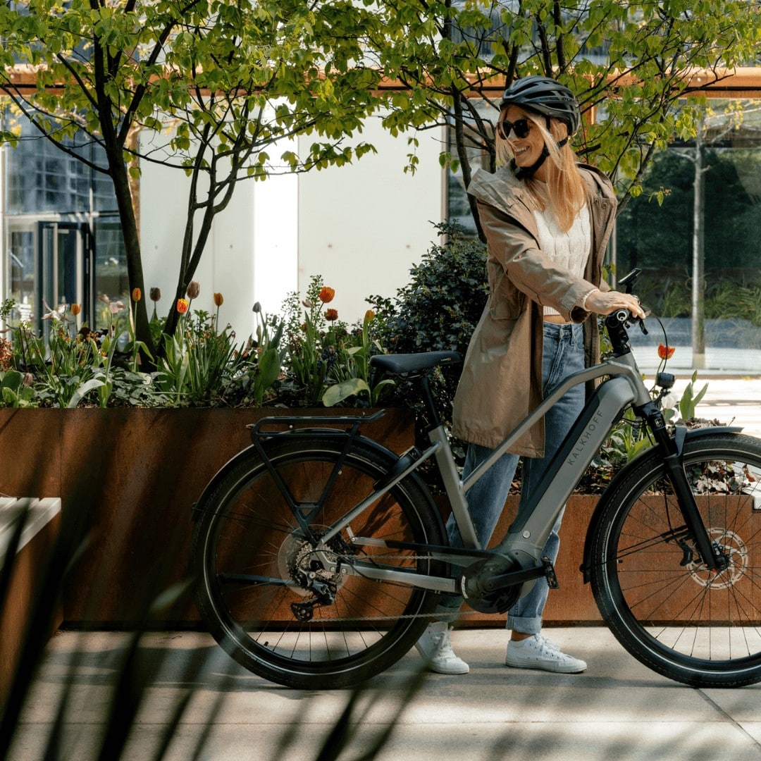 Kalkhoff E-bike Leasing Frau geht mit ihrem Kalkhoff E-Bike durch die Stadt