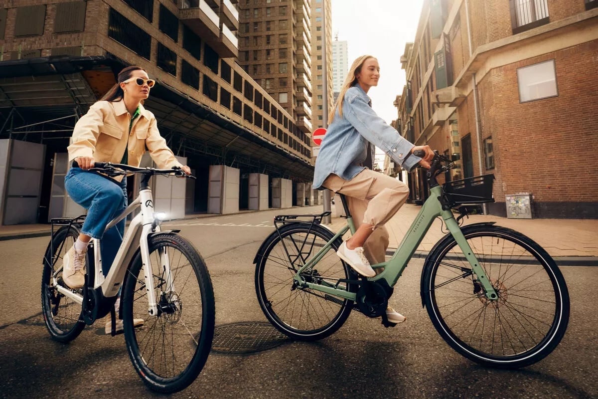 Zwei Frauen fahren mit ihrem Kalkhoff E-Bike Light Modellen durch die Gassen einer Stadt