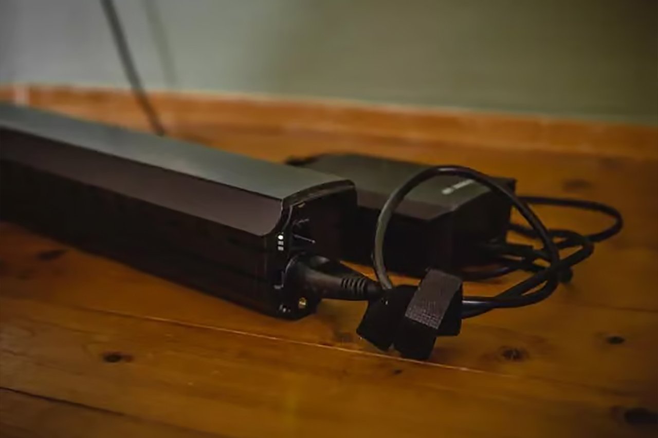 Der Akku sowie das passende Ladegerät liegen auf einem Holztisch