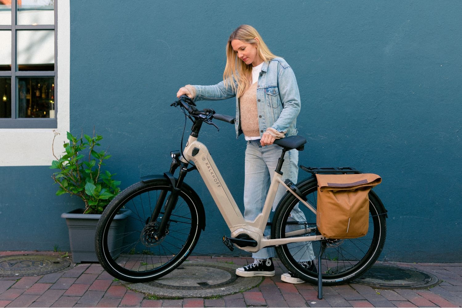 Kalkhoff E-Bike Image 5 excite ABS Frau steht hinter Ihrem beigen Kalkhoff Image 5 excite ABS E-Bike.