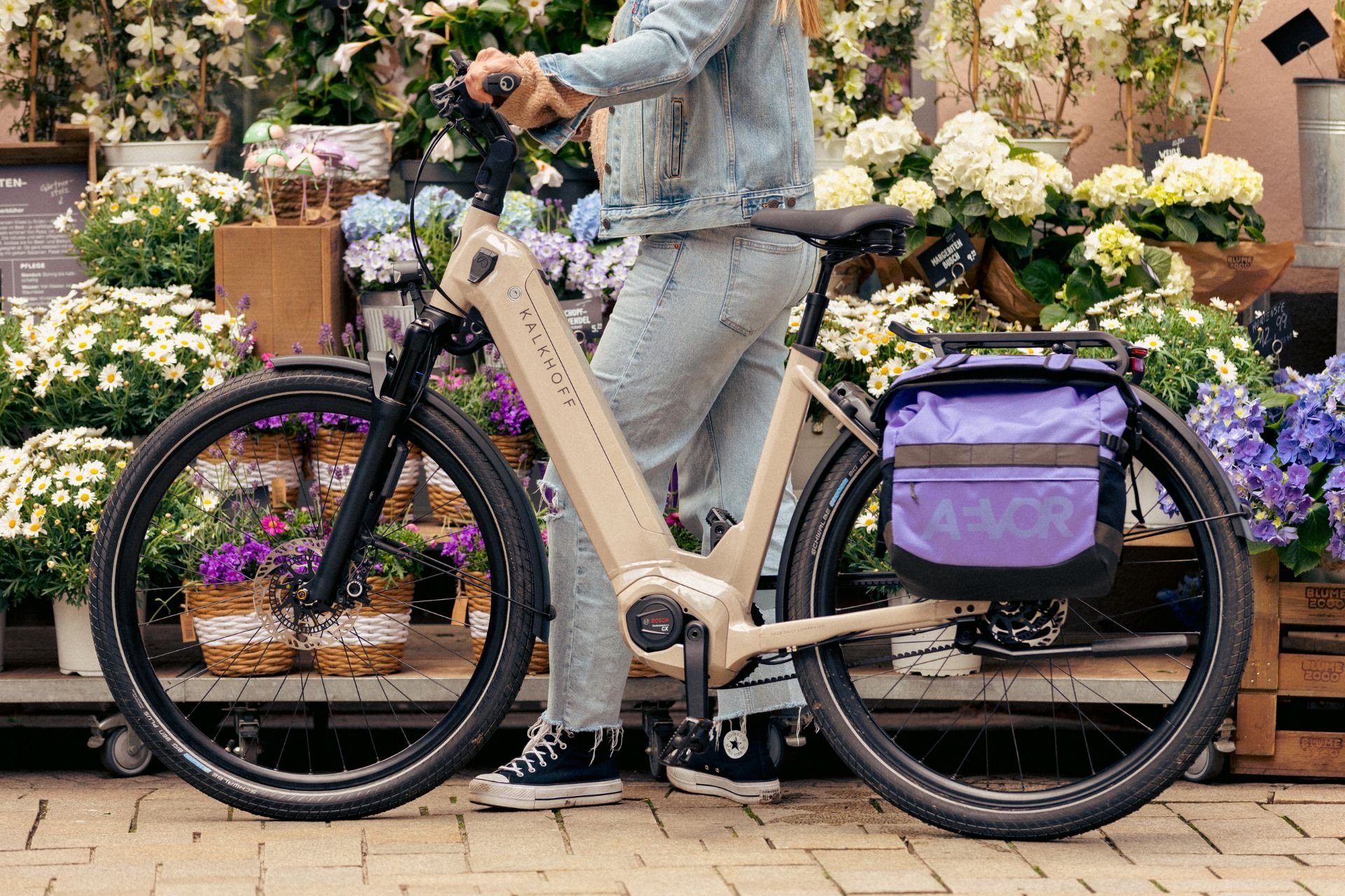 Frau steht mit ihrem Kalkhoff E-Bike vor vielen Blumen
