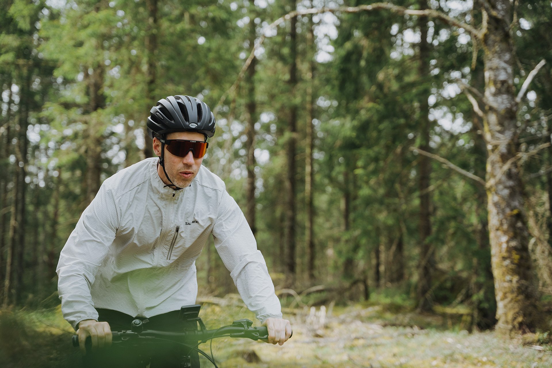 Die Reichweite ist eine der wichtigsten Entscheidungsgrößen beim E-Bike Kauf. Mann mit Helm und Fahrradbrille fährt durch den Wald