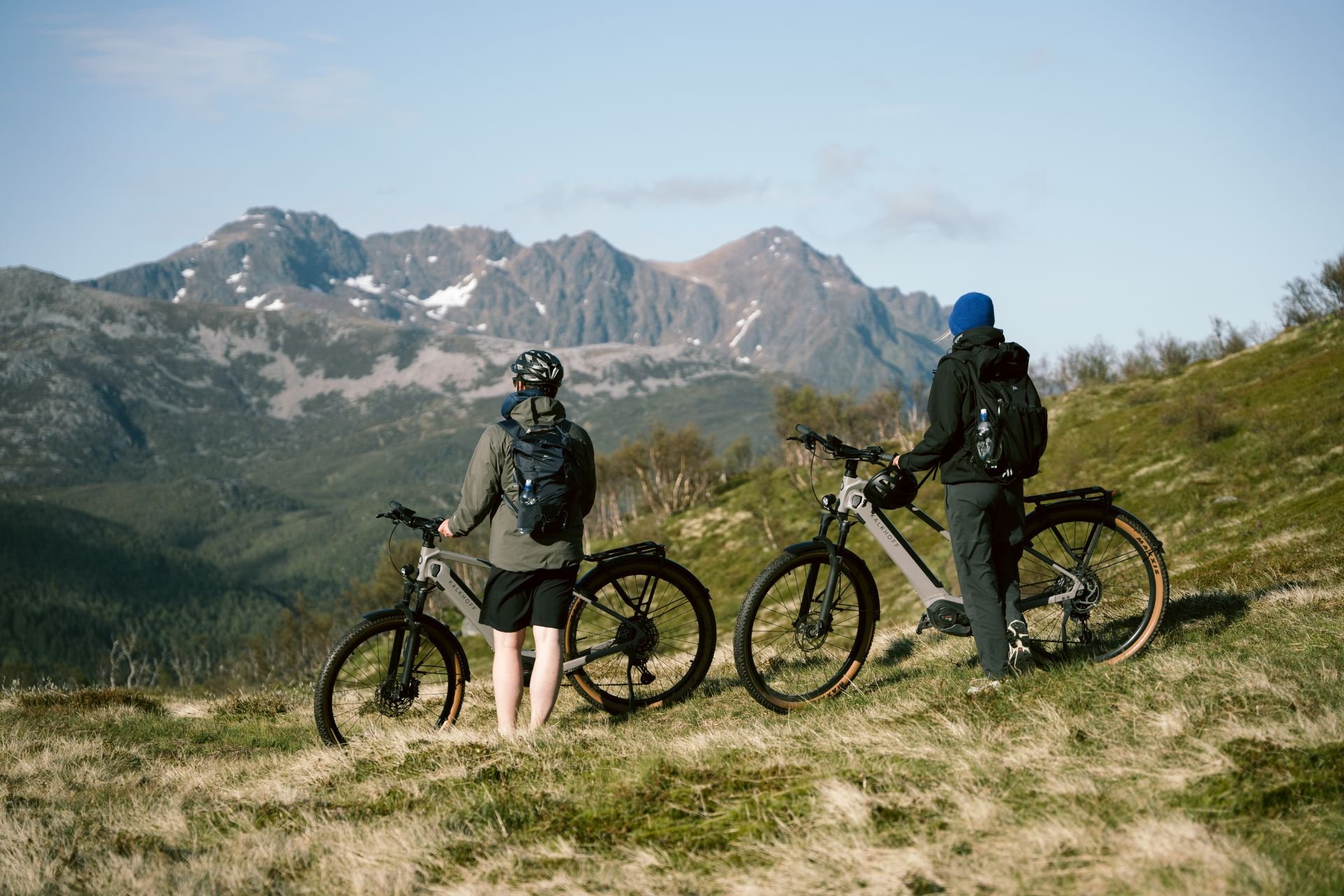 E-Bike Reisen Zwei Männer stehen auf einem Berg und schauen sich die Aussicht an