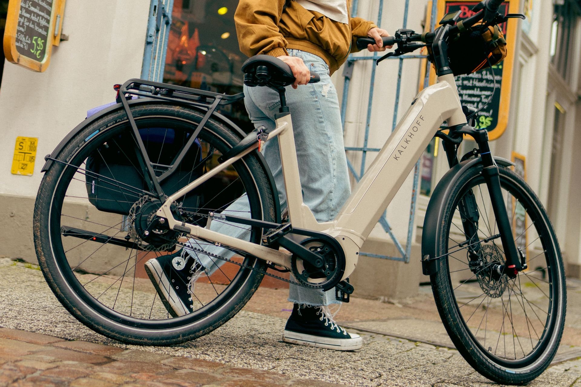 Frau schiebt ihr Kalkhoff E-Bike mit Riemenantrieb durch die Stadt