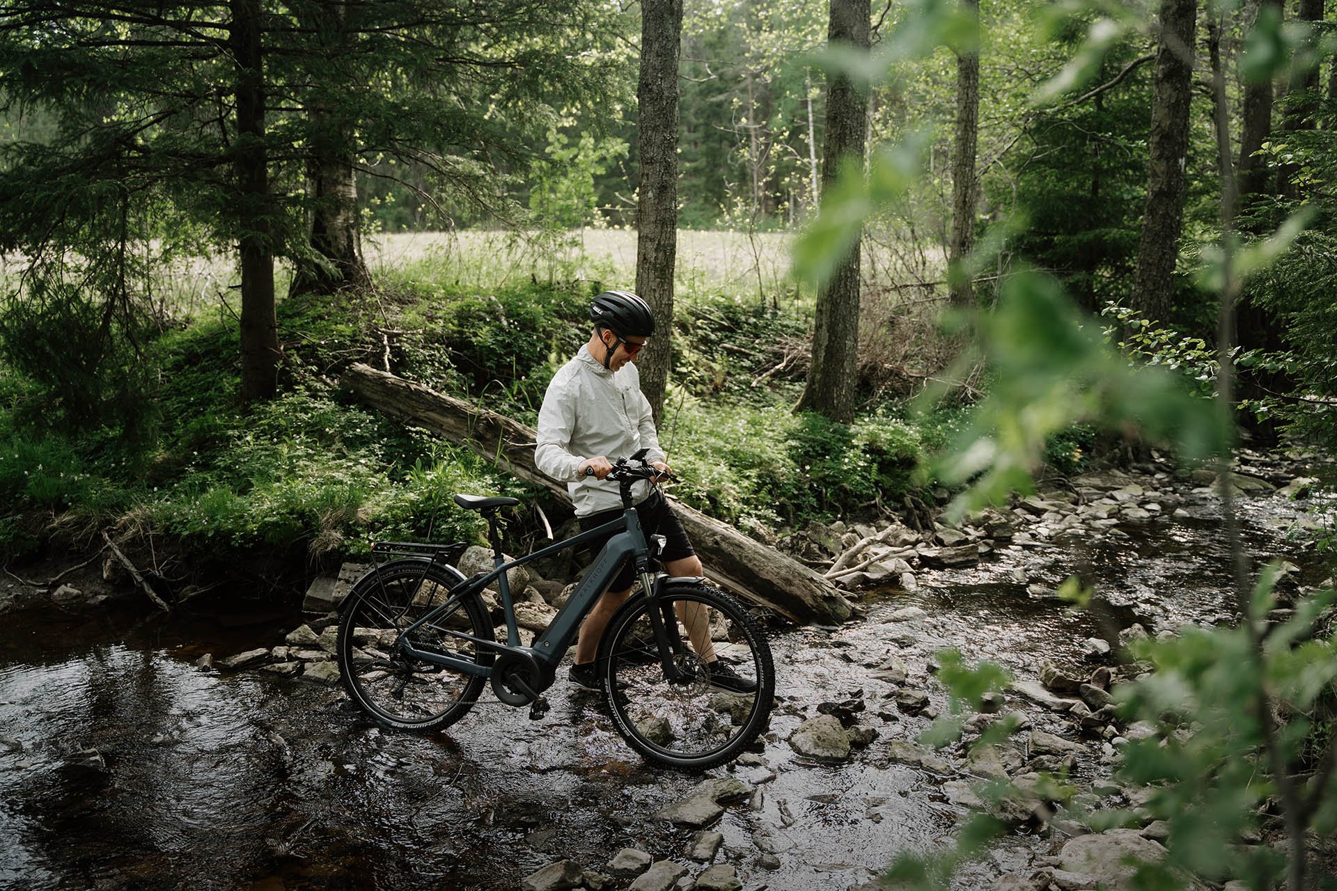 Ein Mann schiebt sein Kalkhoff E- Bike mit Schiebehilfe durch ein Flussbett