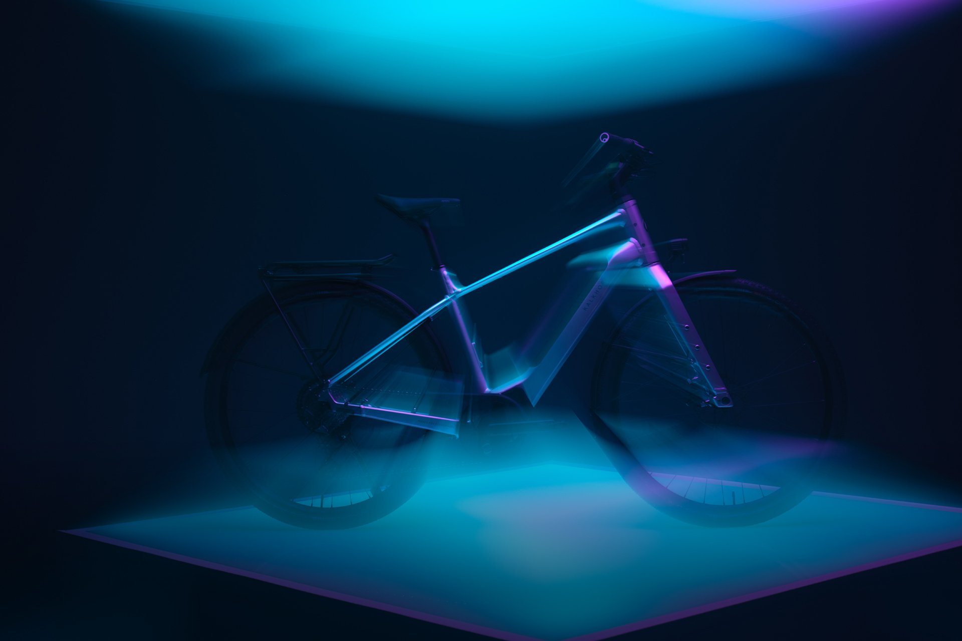 Ein futuristisches E-Bike mit leuchtenden neonblauen und violetten Lichtern, ausgestellt in einem dunklen Raum auf einer beleuchteten Plattform.