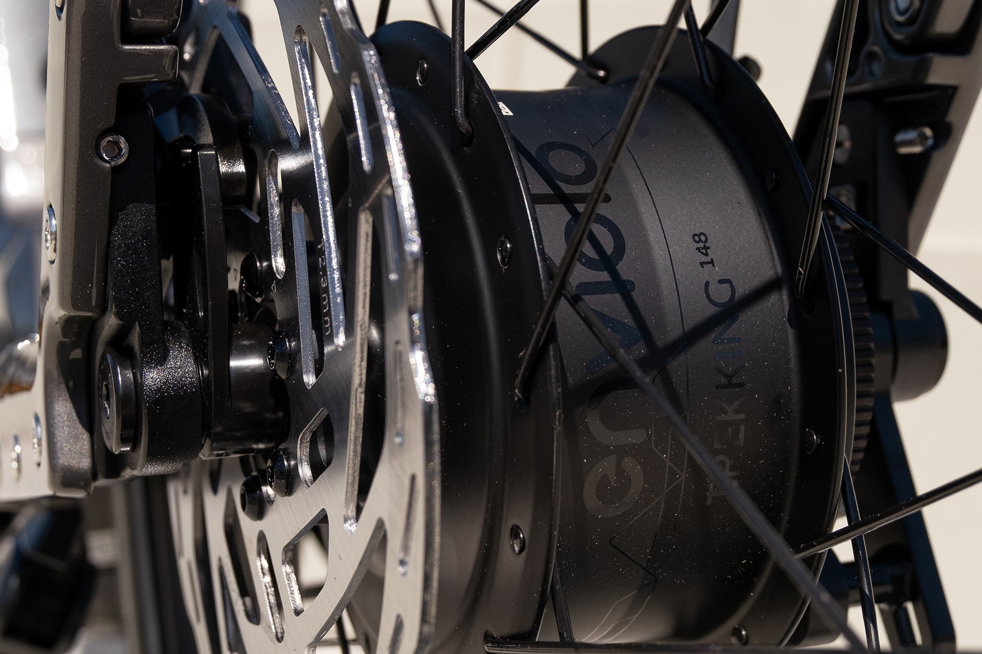 Nahansicht einer Enviolo Nabenschaltung Close-up of an electric bike's hub motor and disc brake, showing detailed metal spokes and engraved branding on the motor housing.