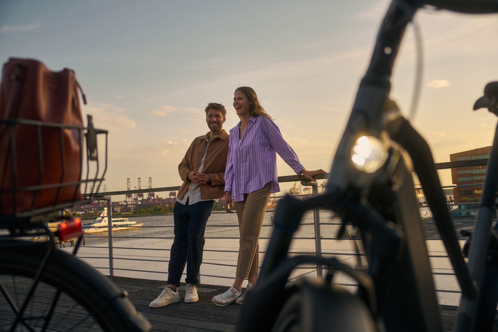 Mann und Frau sind an einem Brückengelände angelehnt und lache