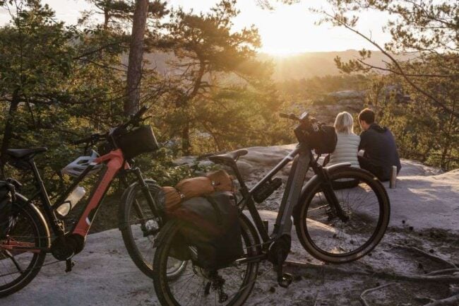 E-Bike Beratung: Optionen beim Kauf Ein Paar sitzt auf dem Boden bei Sonnenuntergang, dahinter stehen zwei Kalkhoff E-Bikes