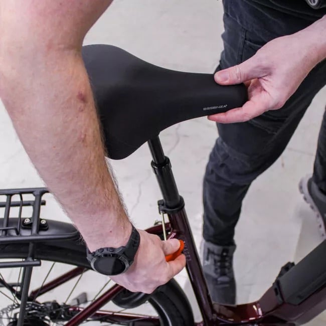 Mann schraubt mit einem Imbusschlüssel die Sattelklemme lose, um den Sattel in der Höhe zu verstellen