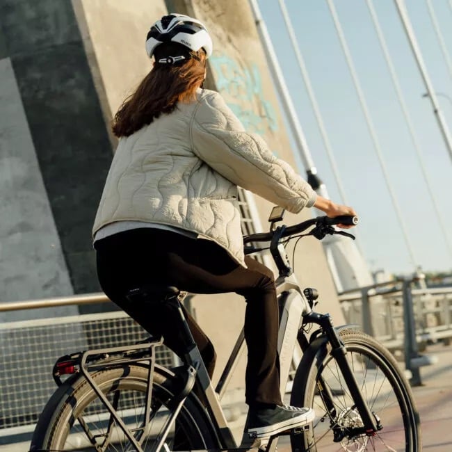 E-Bike fahren lernen: 5 Fahrtechnik-Tipps für Anfänger Man sieht eine Frau von hinten, die gerade ein Kalkhoff E-Bike fährt