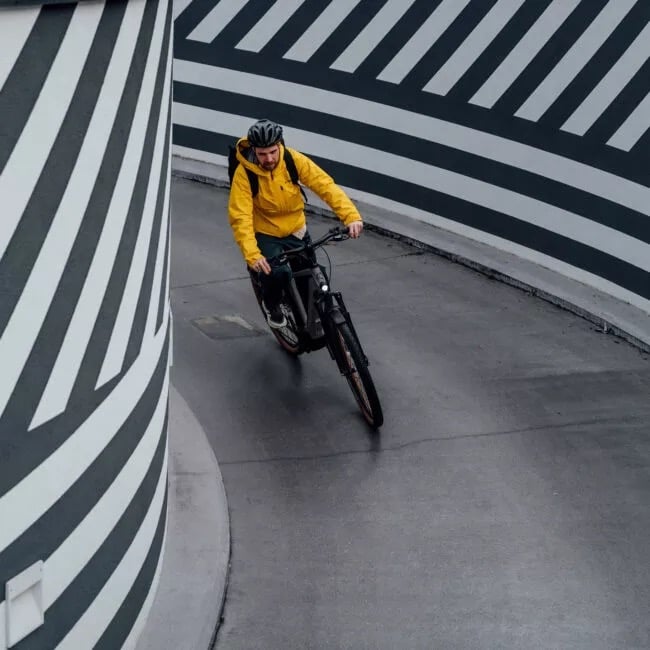 E-Bike fahren lernen: 5 Fahrtechnik-Tipps für Anfänger Mann mit gelber Jacke fährt gerade eine Kurve herunter