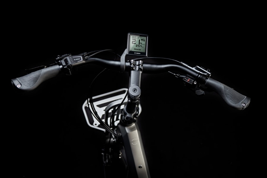 Kalkhoff E-Bike Bosch purion Display Nahaufnahme eines Fahrradlenkers mit Bosch Purion Display, ergonomischen Griffen und Bremshebeln vor schwarzem Hintergrund.