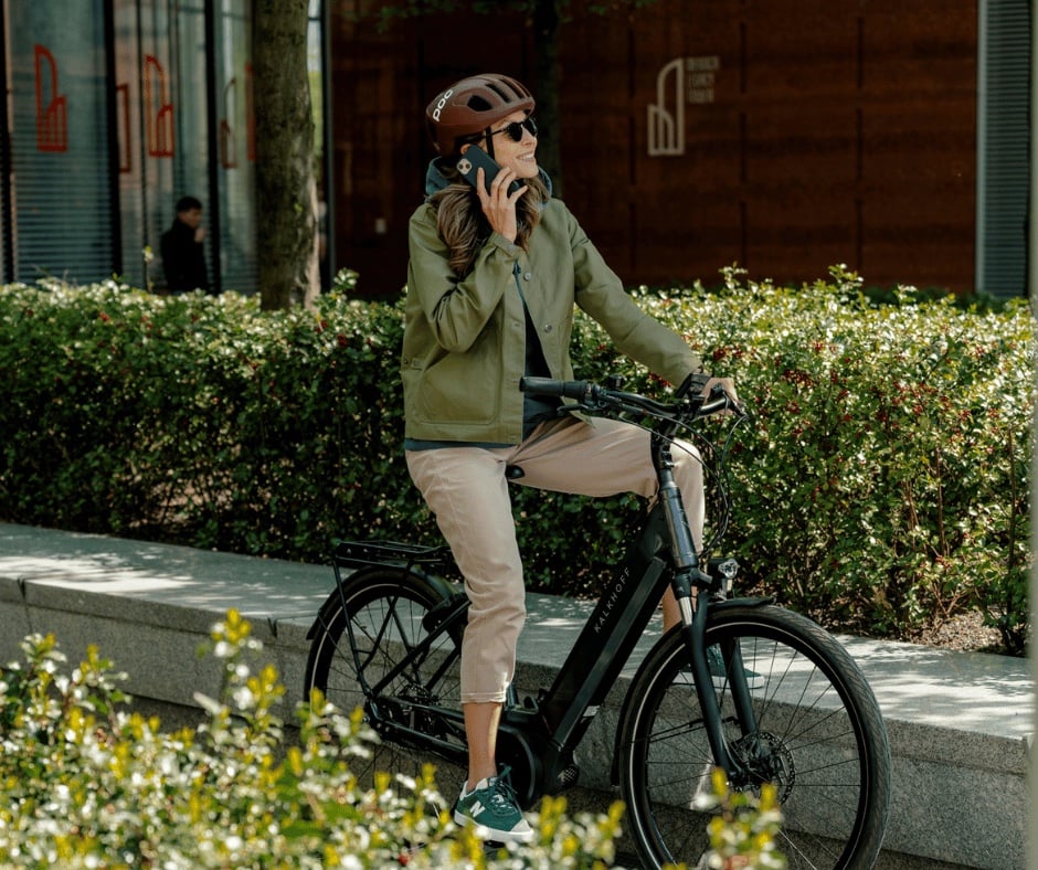 Frau steht mit ihrem Kalkhoff E-Bike und telefoniert