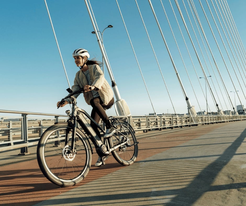 Frau fährt mit ihrem Kalkhoff E-Bike eine Straßenbrücke herunter
